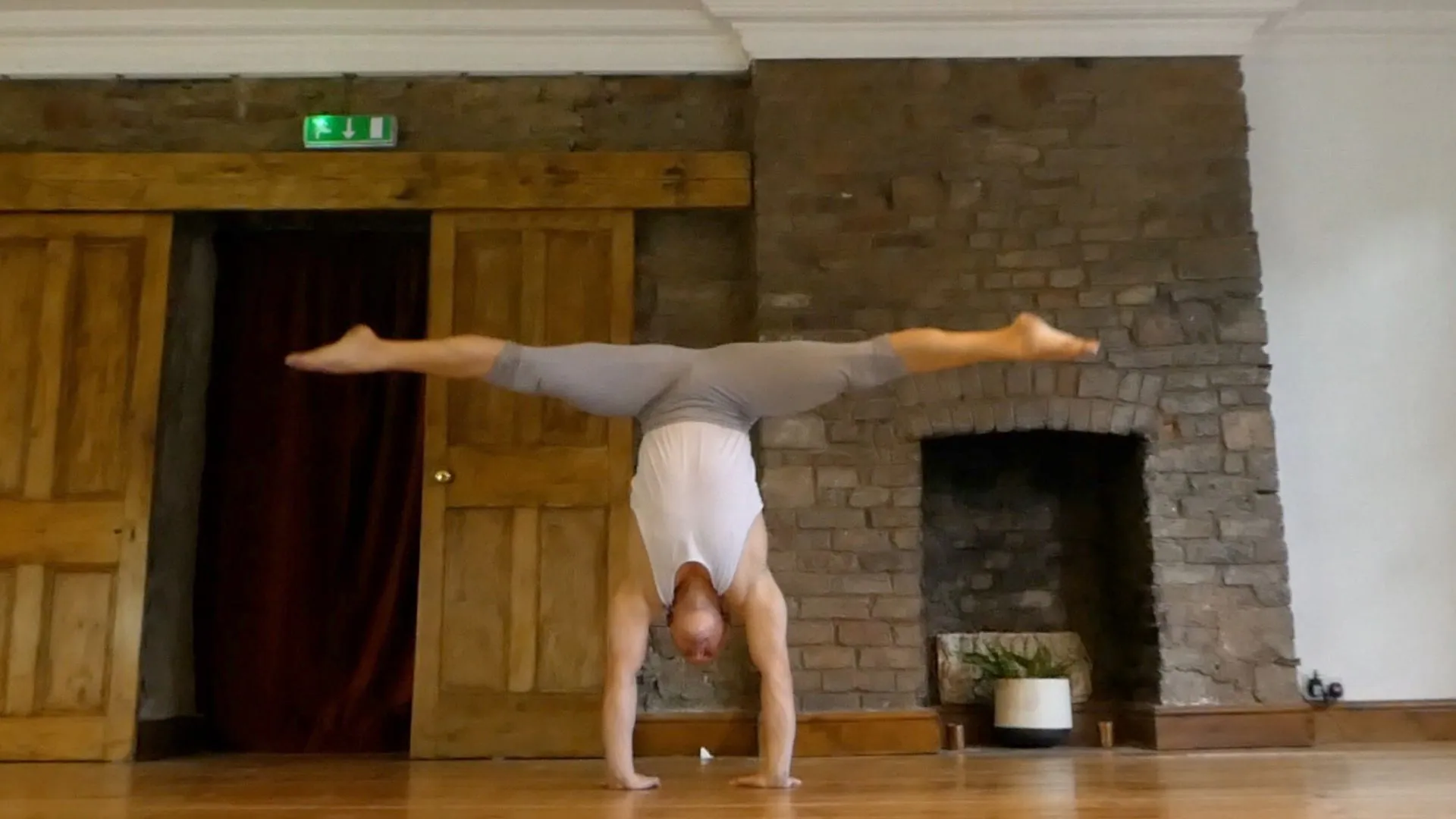 Ben Lowrey in a wide straddle handstand in a studio