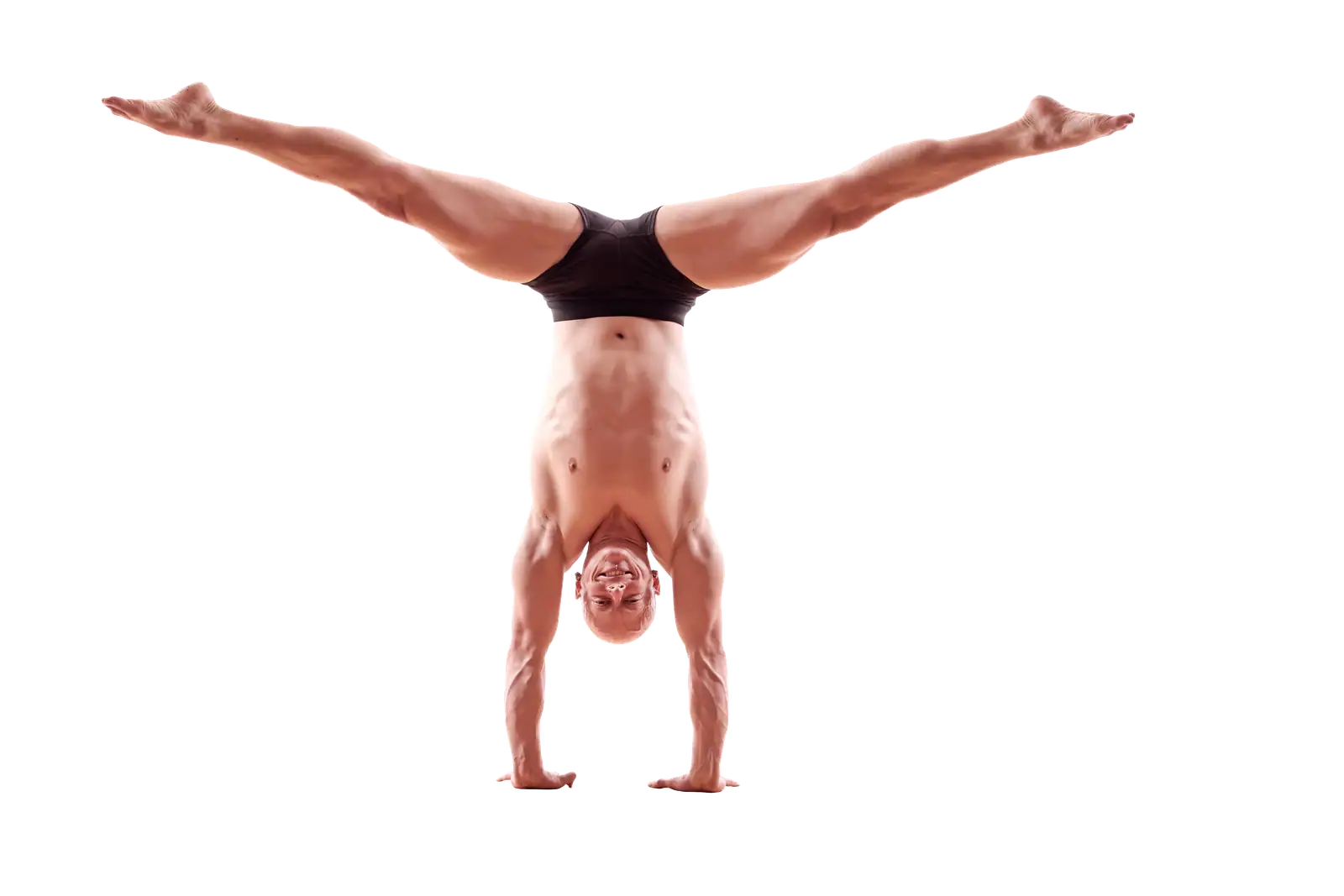 Ben Lowrey smiling upside down in a straddle handstand against a black background