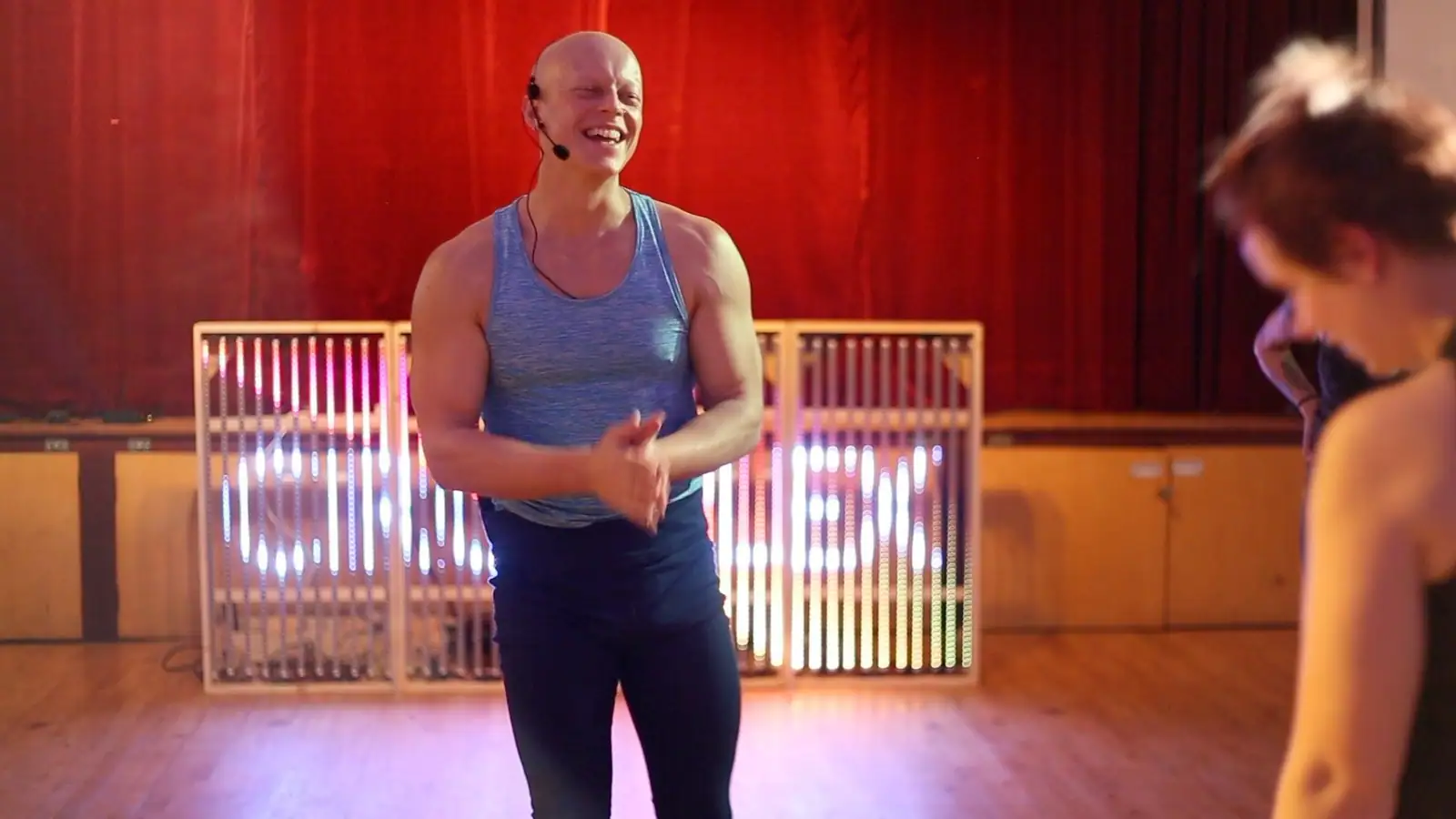Ben Lowrey laughing in front of the glowing CIRCOPLEX LED sign and a red curtain