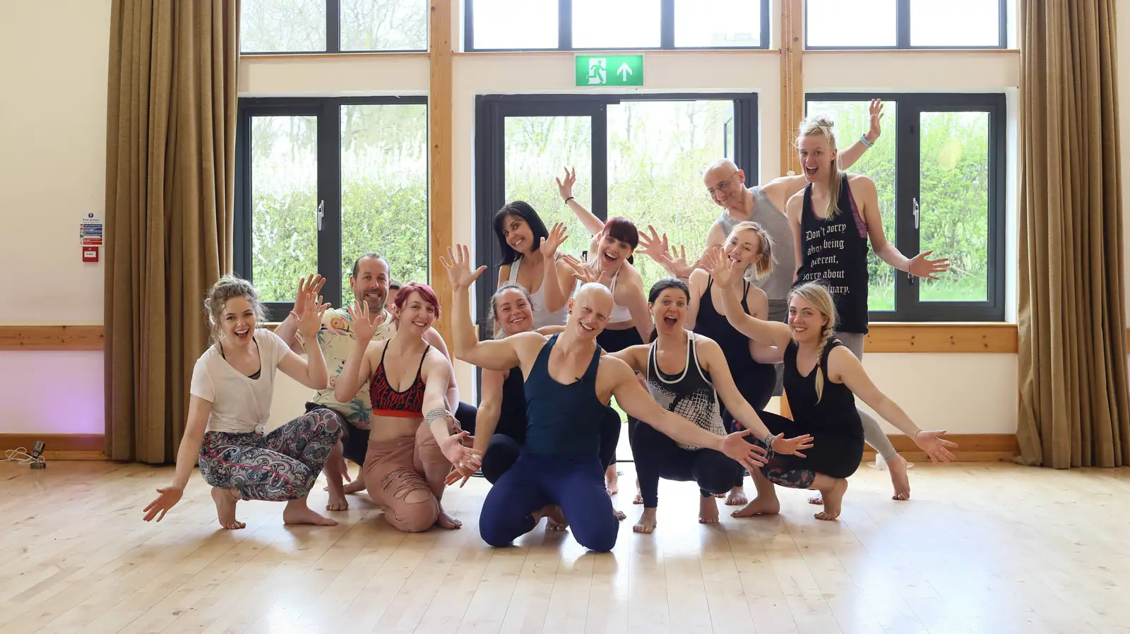 A cheering group with arms out in a bright timber hall, Ben Lowrey crouching at the centre
